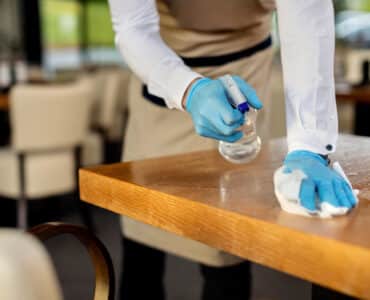 Close up of waiter disinfecting cafe tables after work.